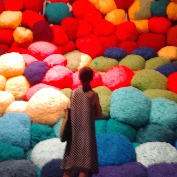 A woman standing in front of a pile of colourful puffy balls.